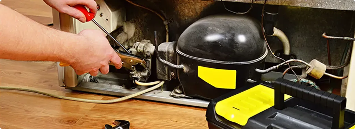 Refrigerator repair technician fixing the compressor and wiring in Shawnee Mission, KS
