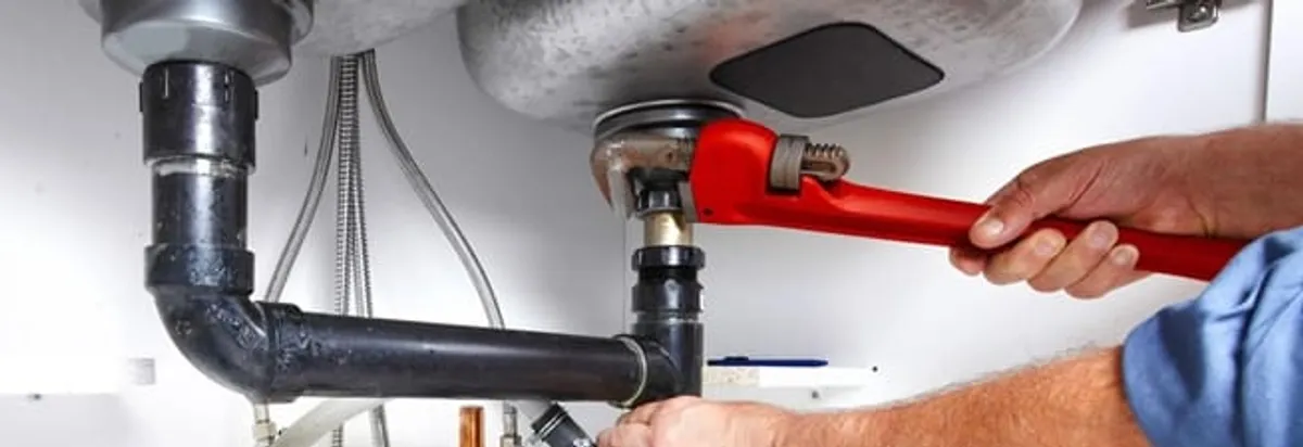 Garbage disposal repair technician tightening the sink drain and disposal connection in Kansas City, KS