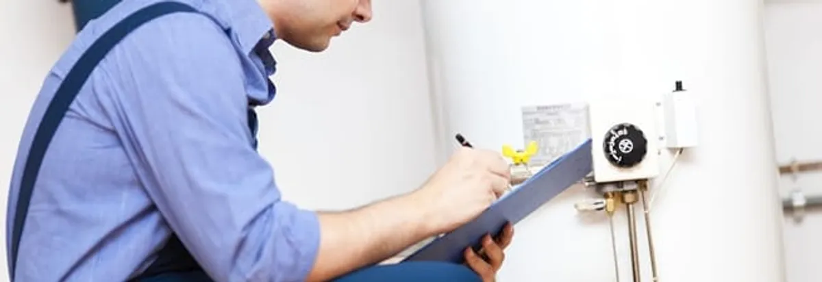 Water heater repair technician inspecting the unit and recording service notes in Kansas City, KS